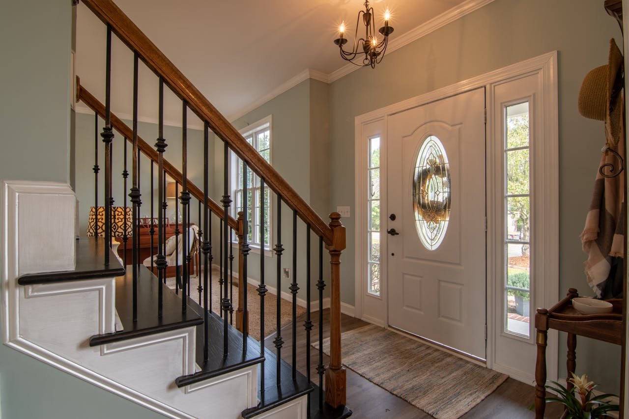 Home Inviting modern hallway with staircase, chandelier, and natural daylight.